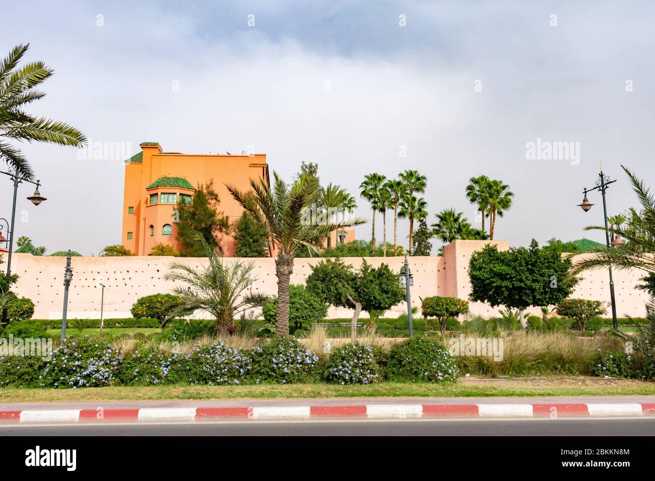 Grande viale con piante verdi e palme con le mura della città di Marrakech Marocco Foto Stock
