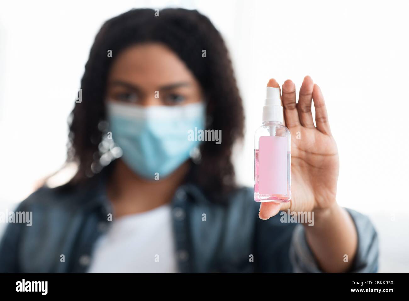 Flacone di disinfettante spray con etichetta vuota nelle mani di Black Woman Foto Stock