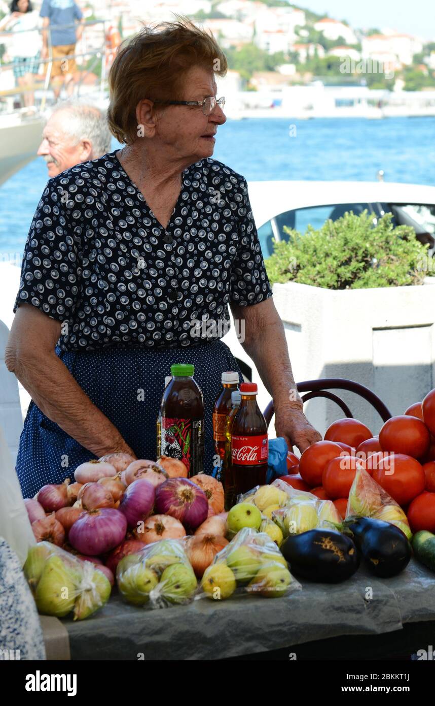 Una donna croata anziana che vende prodotti freschi al mercato di Gruž a Dubrovnik, Croazia. Foto Stock