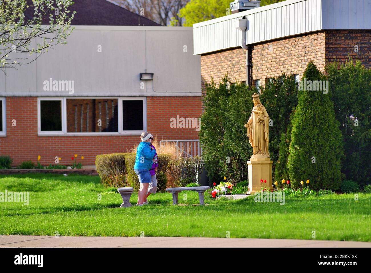 Streamwood, Illinois, Stati Uniti. Due donne finiscono di pregare in un santuario in un cortile come alternativa alla partecipazione in chiesa servizi. Foto Stock
