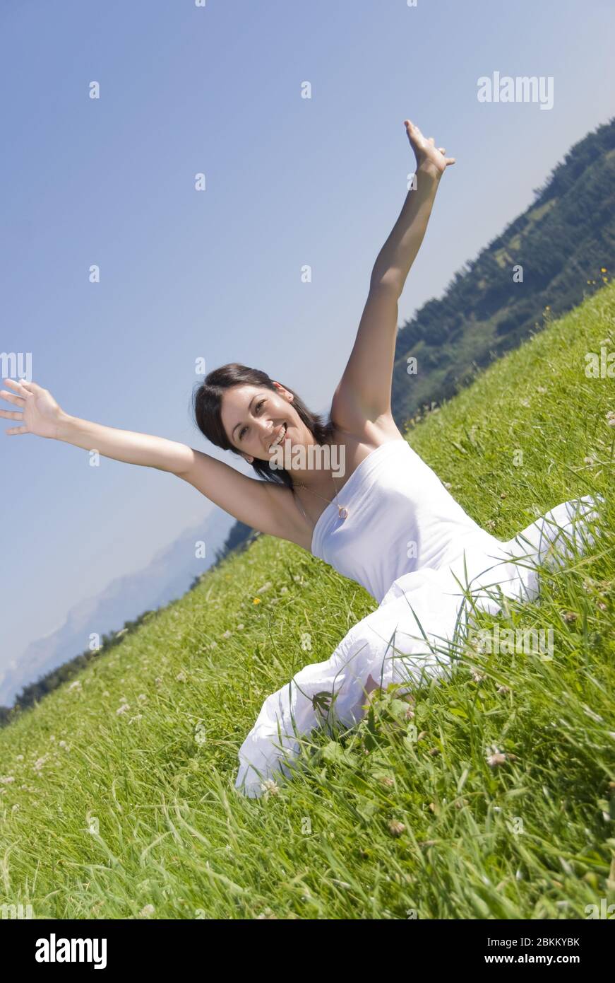 Junge glueckliche Frau streckt ihre Haende in den Himmel, MR: Sì Foto Stock