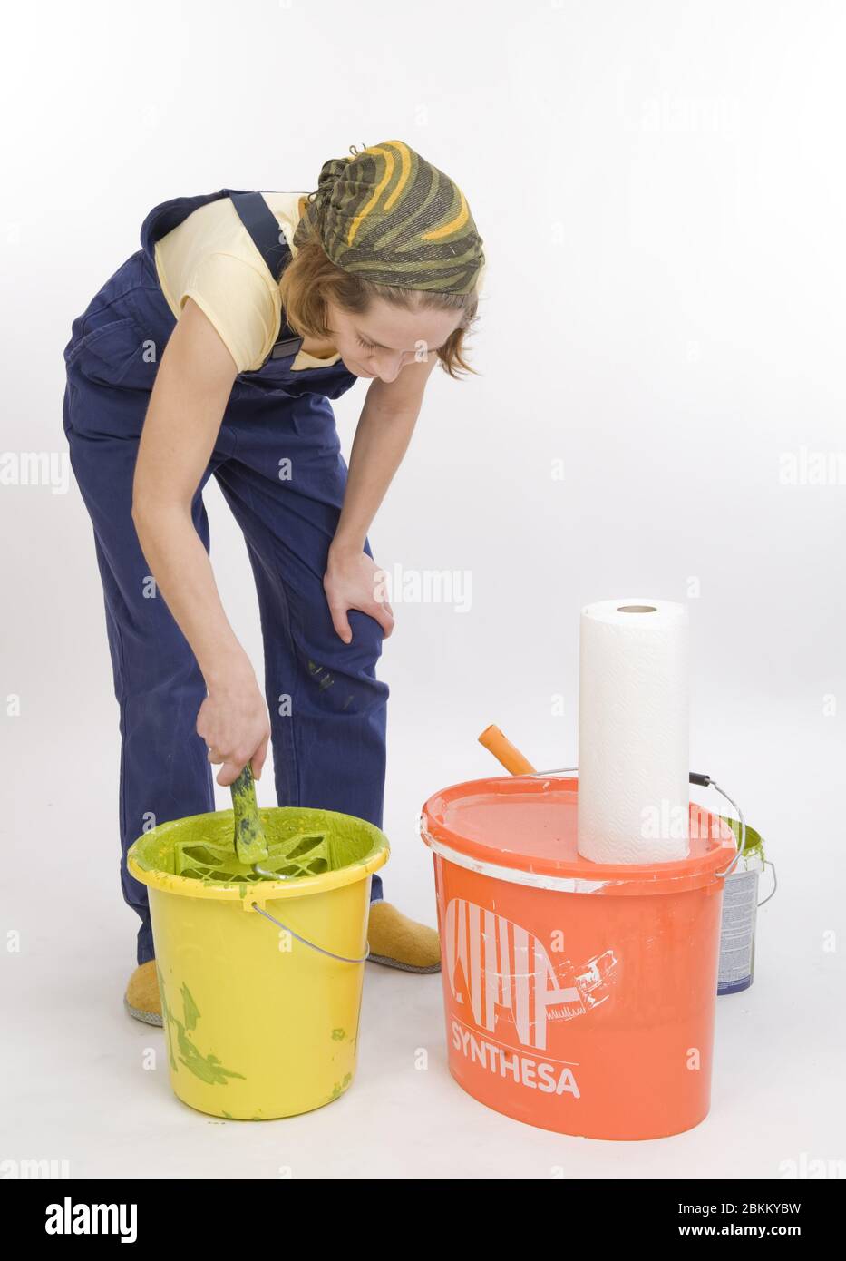 Junge Frau renoviert die Wohnung und ruehrt einen Eimer mit Farbe an, MR: Sì Foto Stock