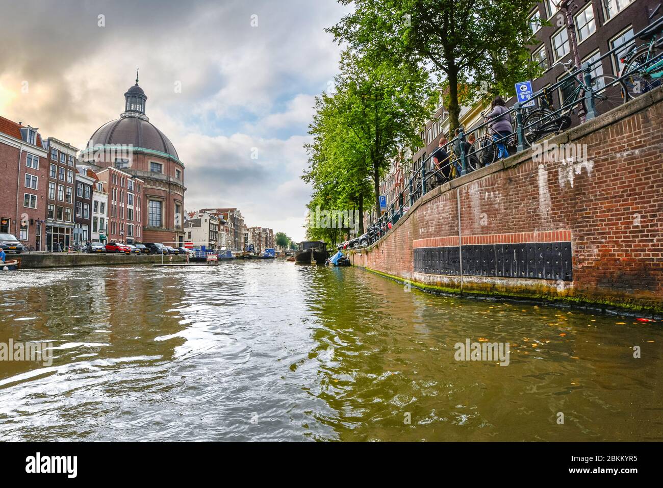 Livello acqua vista dal canale Singel ad Amsterdam, nei Paesi Bassi con il Round chiesa luterana o Ronde Lutherse Kerk in vista su un nuvoloso giorno di autunno Foto Stock
