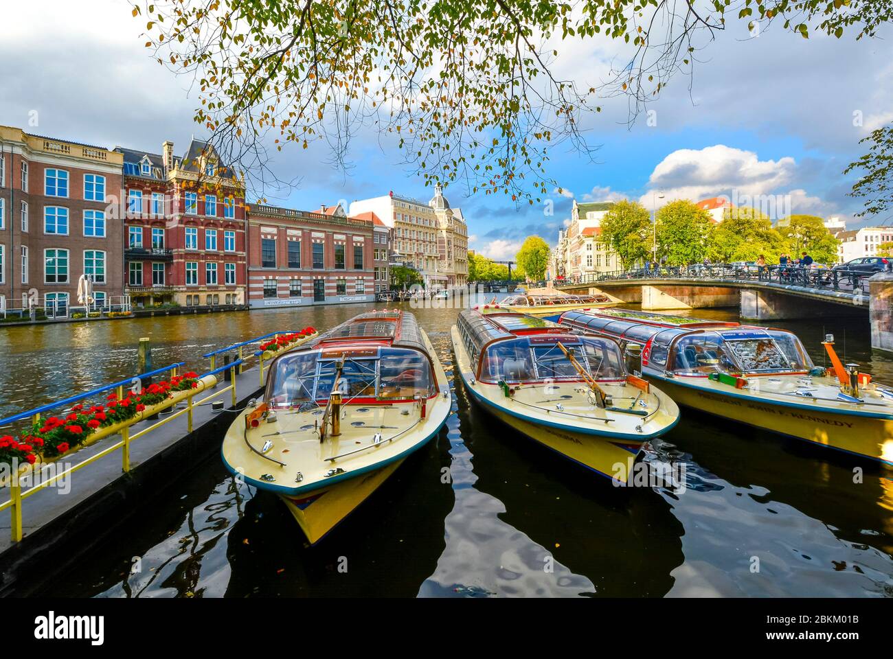 Colorato di giallo e rosso barche tour di attendere in linea per passeggeri per turismo su un importante canale di Amsterdam, Paesi Bassi Foto Stock