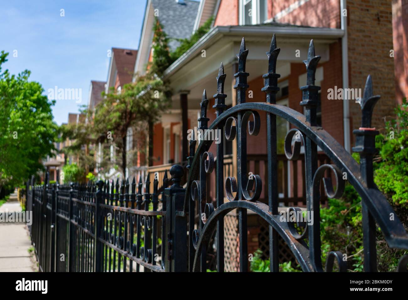 Top of a Fancy Black Metal Fence di fronte Una fila di vecchie case in Logan Square Chicago Foto Stock