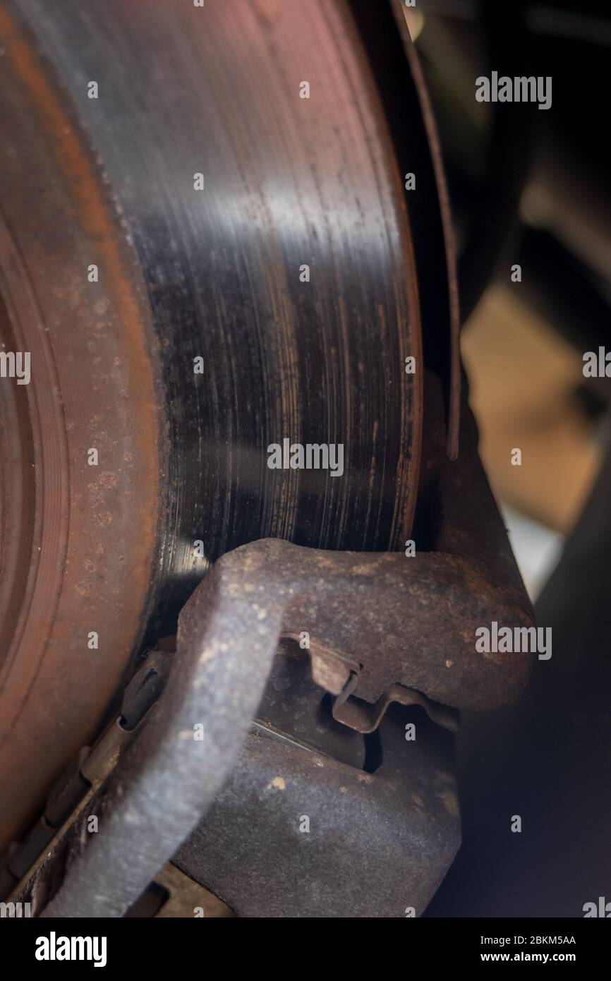 Un complessivo freno a disco per auto che mostra una pastiglia del freno contro un rotore arrugginito Foto Stock