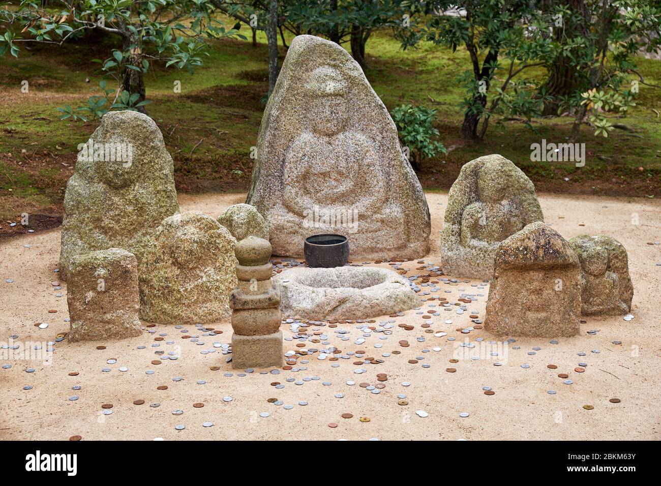 La vista delle immagini e delle monete buddiste di Jizo che i visitatori hanno gettato nel parco del tempio di Kinkaku-ji. Kyoto. Giappone Foto Stock