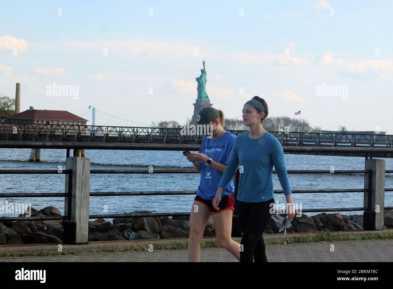 3 maggio 2020, Jersey City, New Jersey, USA: Queste donne, una con maschera, camminano nel vialetto che attraversa Liberty state Park, vicino alla Statua della libertà di Jersey City. Questo è uno dei siti all'aperto con i club di golf del New Jersey riaperto nel fine settimana, nonostante una settimana triste che ha visto il numero di morti giornaliere superare il numero di vittime dello Stato di New York prima di scendere. ''la riapertura è un test enorme, '' ha avvertito Gov. Phil Murphy. I visitatori devono aderire alle distanze sociali e le coperture facciali sono fortemente incoraggiate. nel fine settimana sono emersi 3,000 nuovi casi. Lo stato registra quasi 8,000 coronav Foto Stock