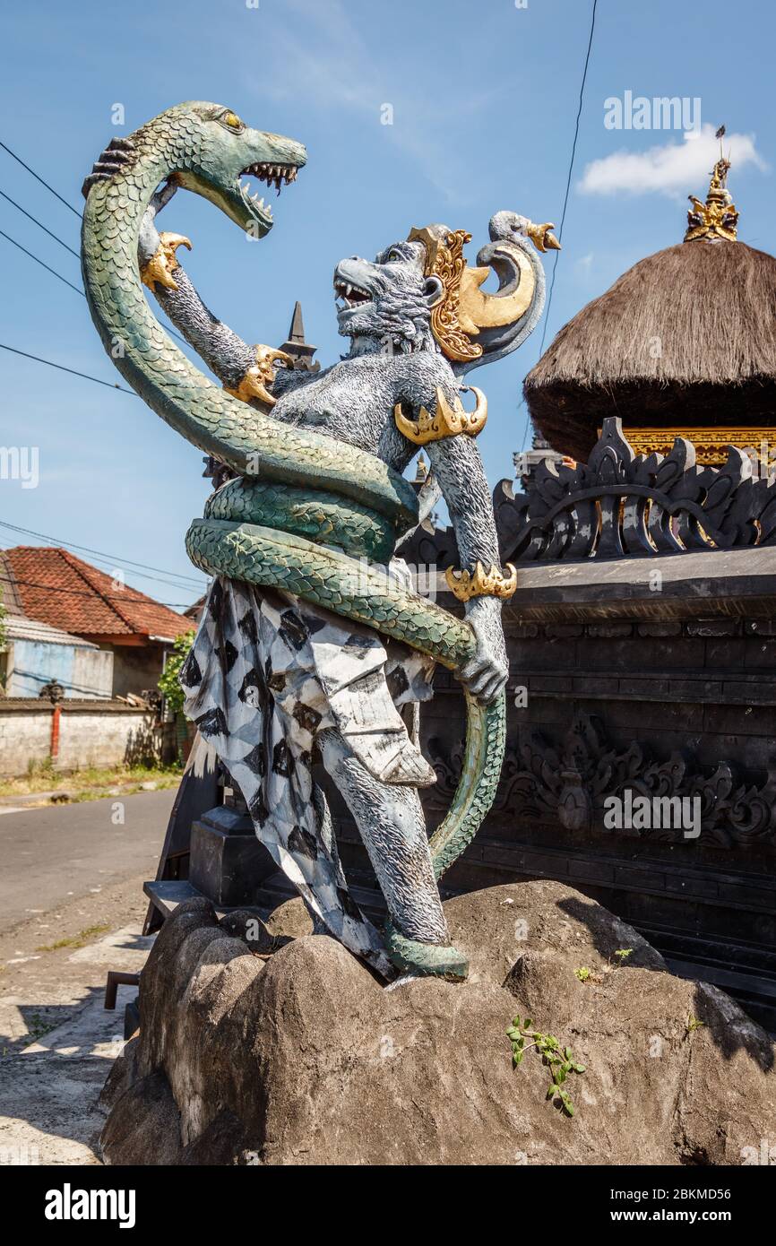 Statua di Hanuman, dio indù e divina scimmia (vanara) compagno del dio Rama, combattendo naga (serpente). Bali, Indonesia. Immagine verticale. Foto Stock