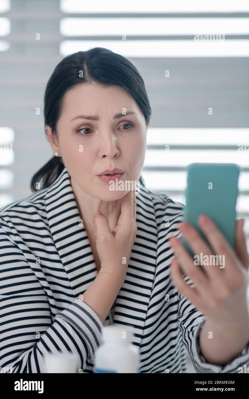 Donna adulta preoccupata e attenta che guarda lo smartphone Foto Stock