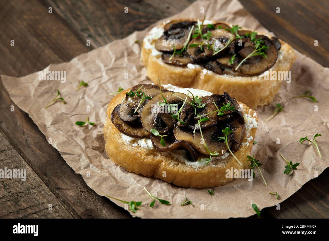 Bruschetta con formaggio, funghi e microgredi alla pergamena. Foto Stock