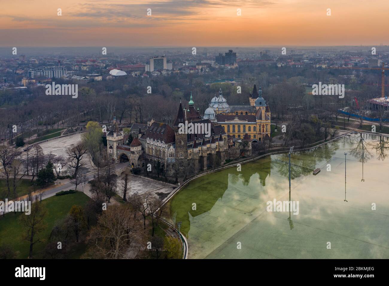 Budapest, Ungheria - veduta aerea del Castello di Vajdahunyad nel Parco della Città (Varosliget) con il Lago del Parco della Città e una bella alba dorata dietro Foto Stock