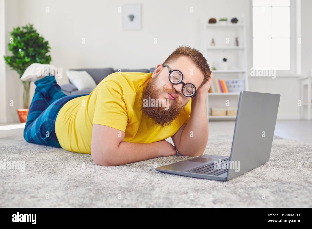 Online dating chat video chat call.Funny Fat uomo in occhiali di uno stolto con un laptop su una data online videochiamata chat applicazione in camera a casa. Foto Stock