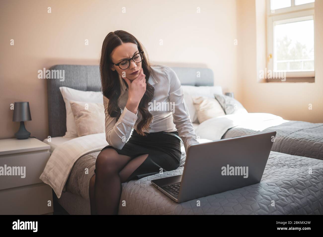 Donna d'affari in viaggio d'affari seduto in camera d'albergo e lavorando su un computer portatile. Foto Stock