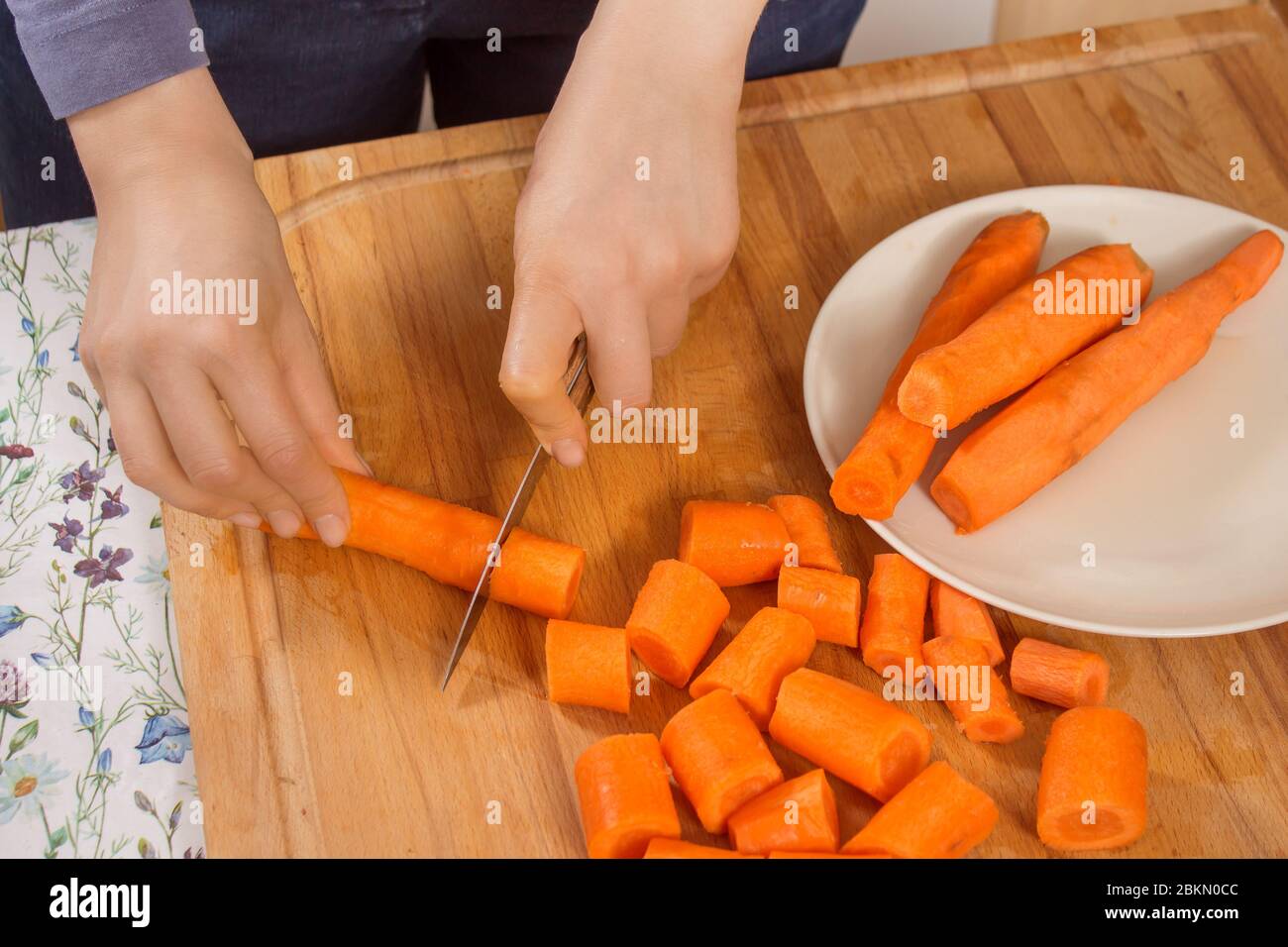 La donna taglia le carote sul tavolo da cucina con un coltello