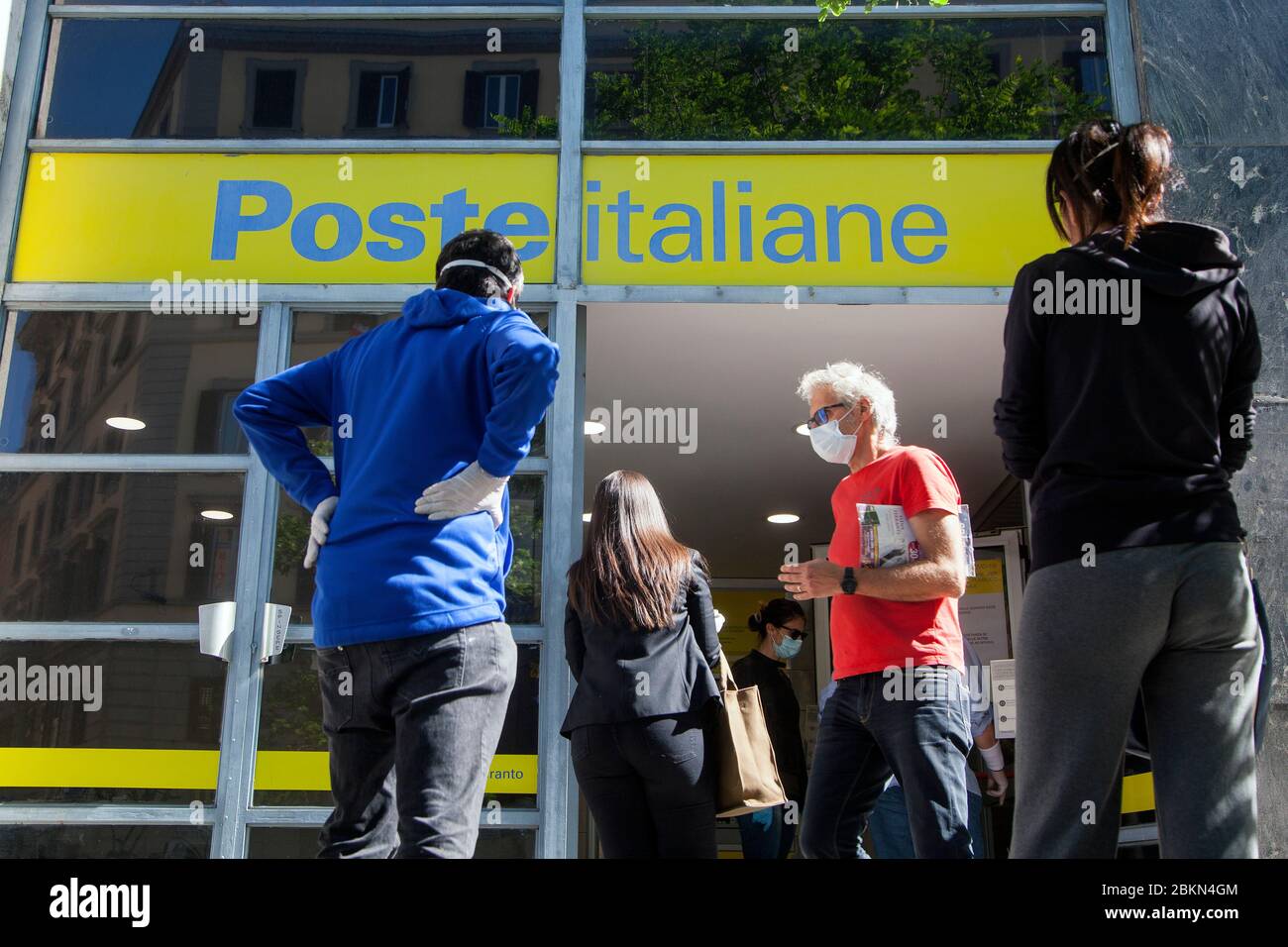 La coda dei pedoni che indossano una maschera protettiva fuori dall'ufficio postale Poste Italiane Foto Stock