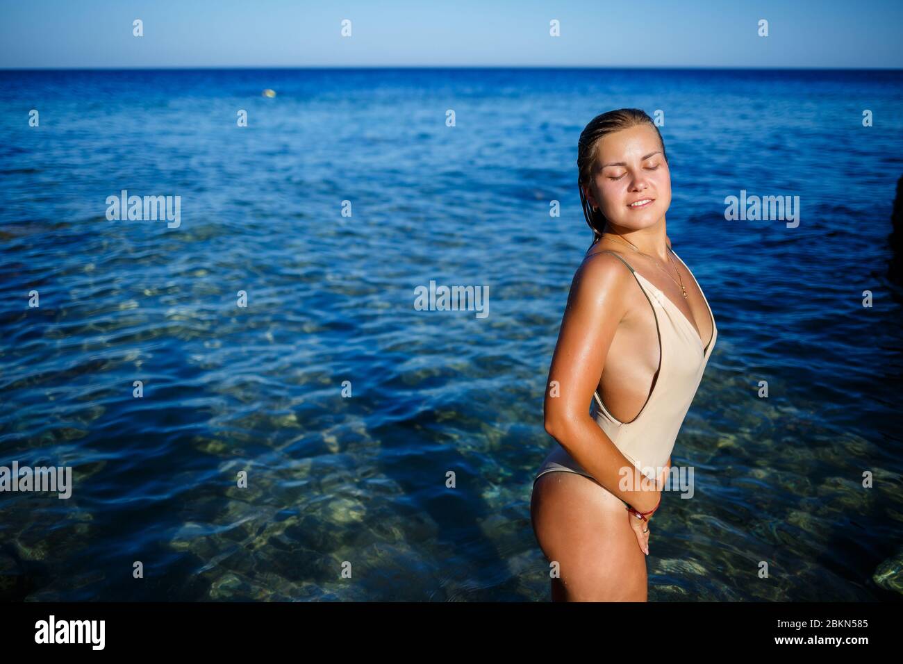 Una ragazza con una bella figura in un costume da bagno beige nell'acqua  blu del Mar Rosso. Si alza al sole Foto stock - Alamy