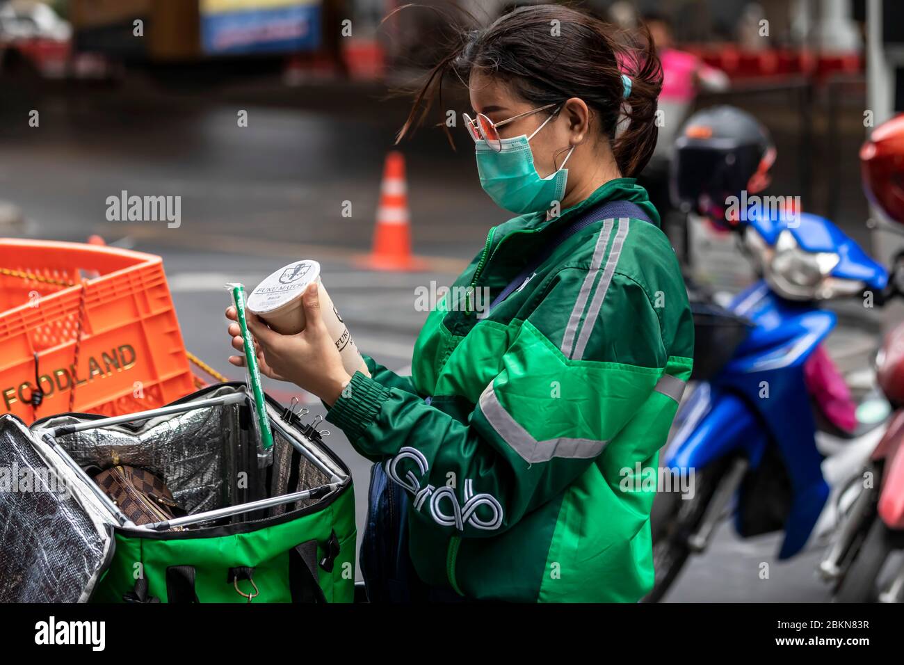 Afferrare il pilota motociclista di consegna di cibo con maschera facciale durante la pandemia di Covid 19, Bangkok, Thailandia Foto Stock