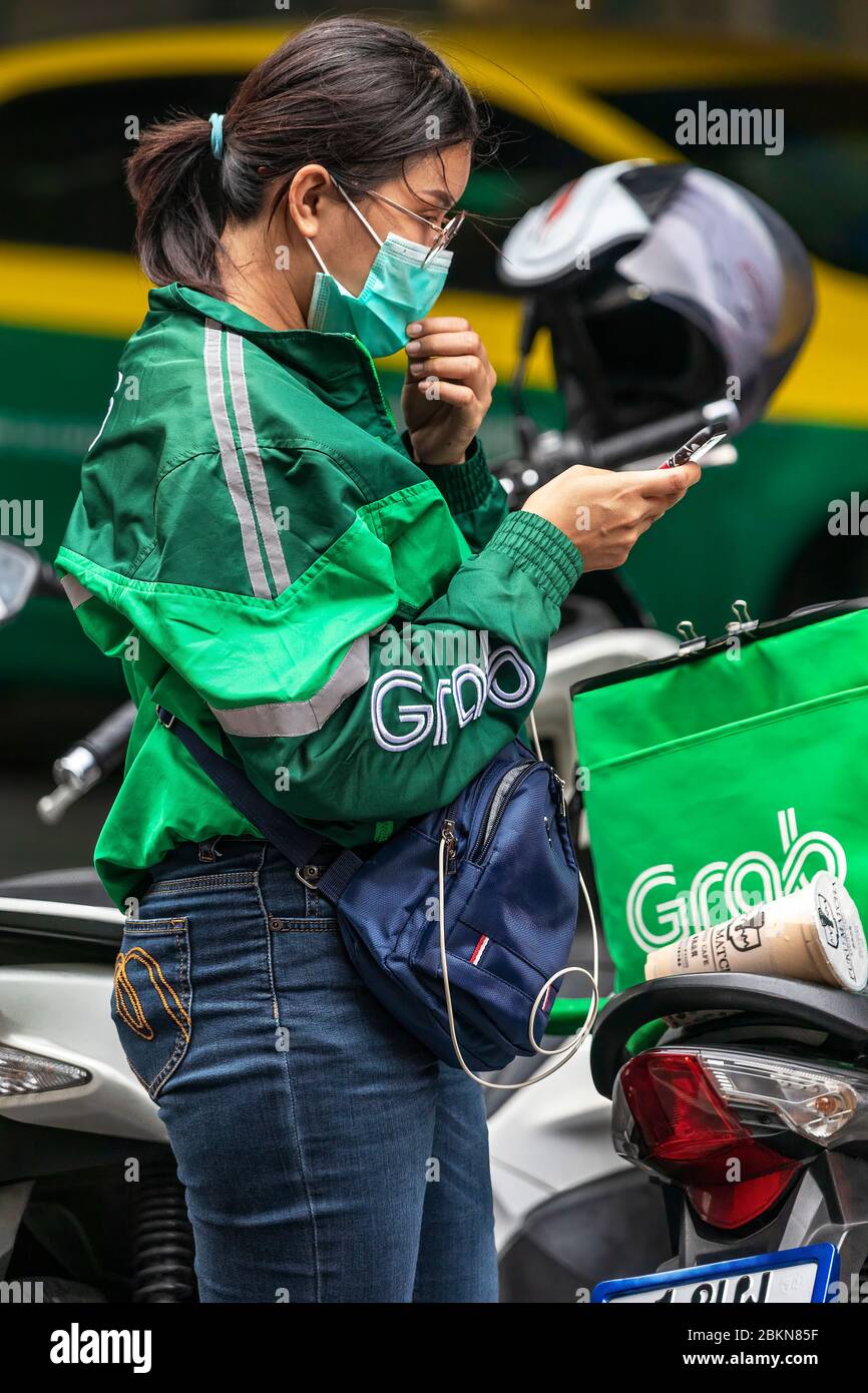 Afferrare il pilota motociclista di consegna di cibo con maschera facciale durante la pandemia di Covid 19, Bangkok, Thailandia Foto Stock
