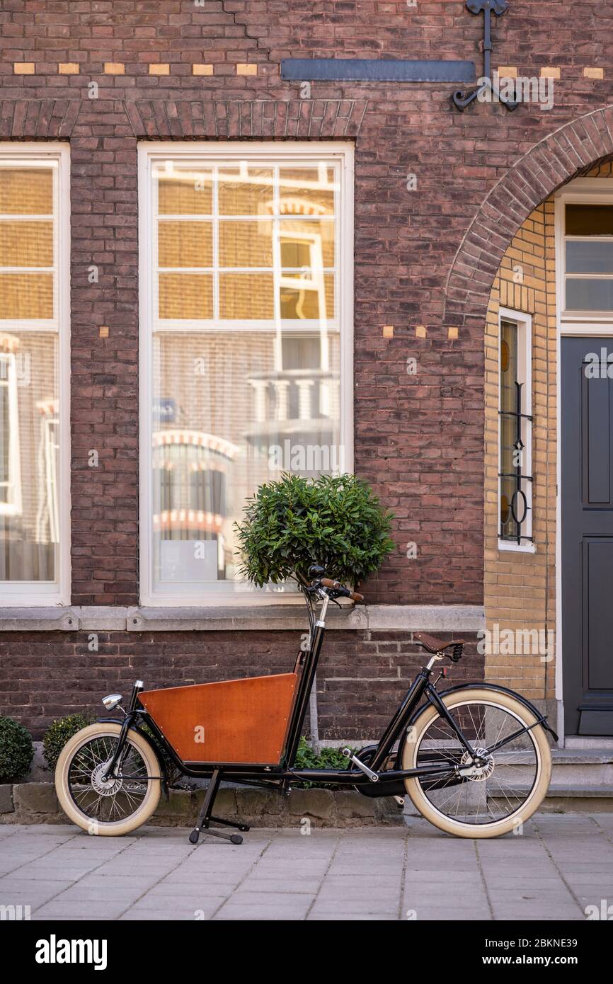 Tipica bicicletta olandese parcheggiata di fronte a una casa. I genitori urbani moderni usano queste bici del portatore per trasportare i loro generi alimentari o bambini Foto Stock