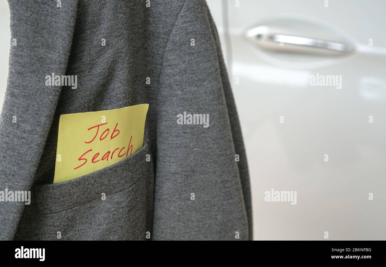 Ricerca di lavoro, parole in rosso su una carta gialla bloccata fuori dalla tasca di una giacca grigia. Auto bianca sullo sfondo. Spazio di copia. Foto Stock