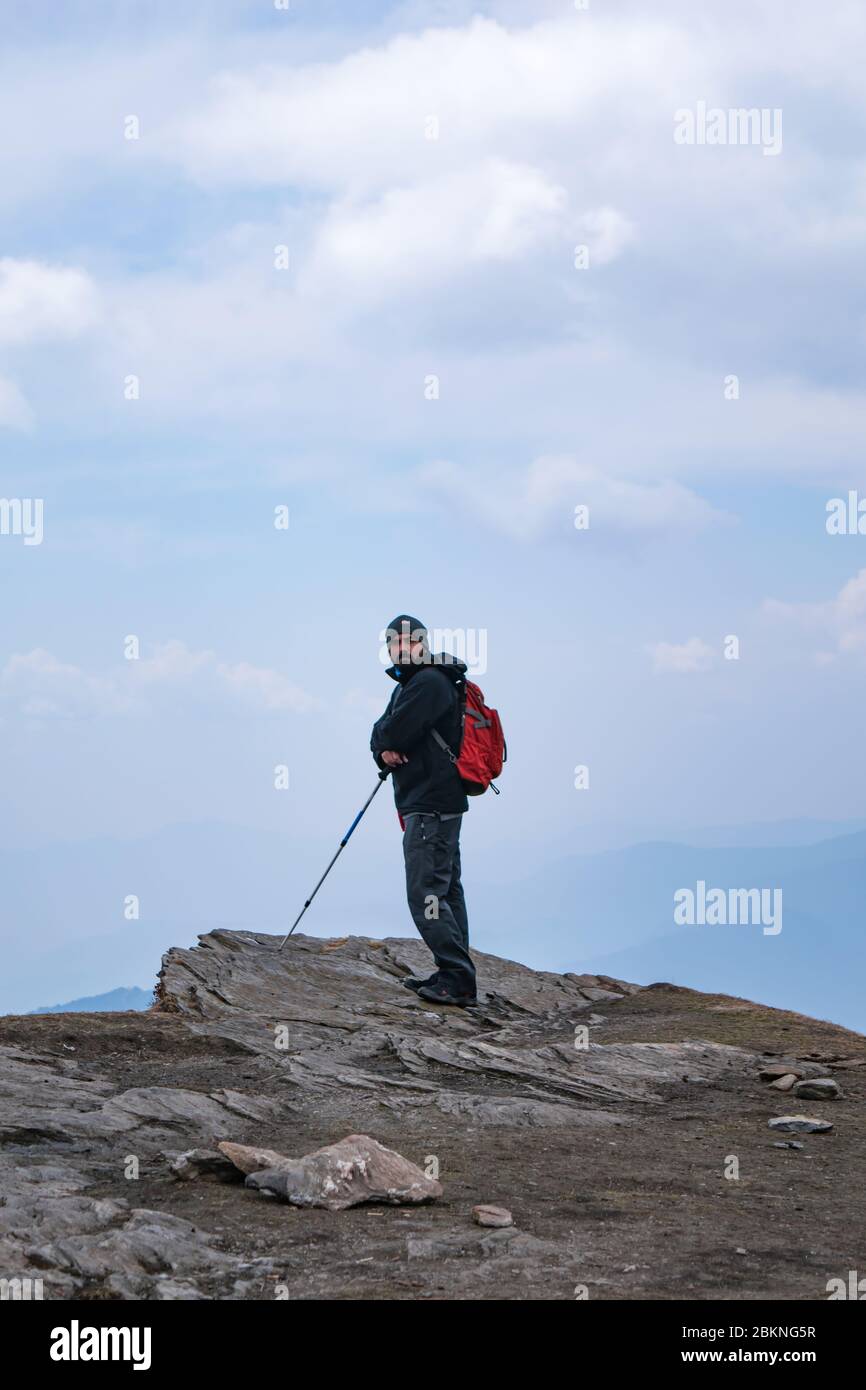 Giovani escursionisti indiani con zaino e palo da trekking in piedi al bordo di una scogliera di montagna Foto Stock