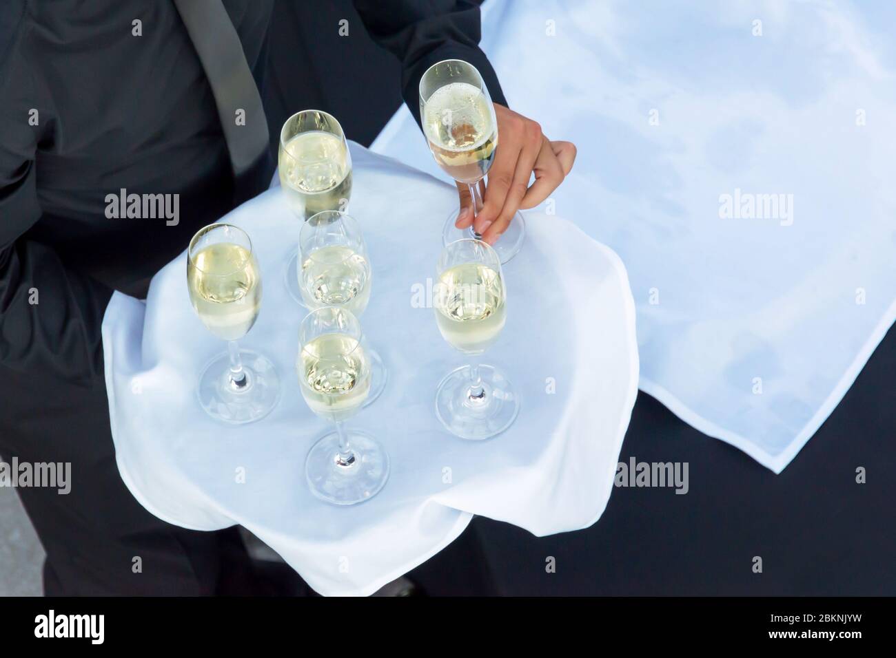 Vista dall'alto di un cameriere che tiene un vassoio con bicchieri di champagne o vincita bianca, bevande di catering in un cocktail party Foto Stock