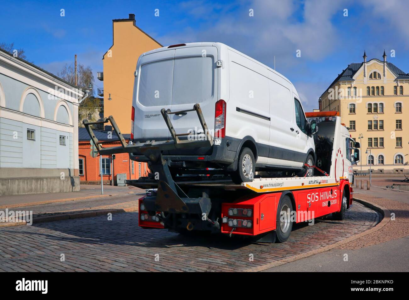 Il rimorchio hinaus Sjöberg Oy porta un furgone bianco lungo la strada in città, vista posteriore. Helsinki, Finlandia. Aprile 29, 2020. Foto Stock