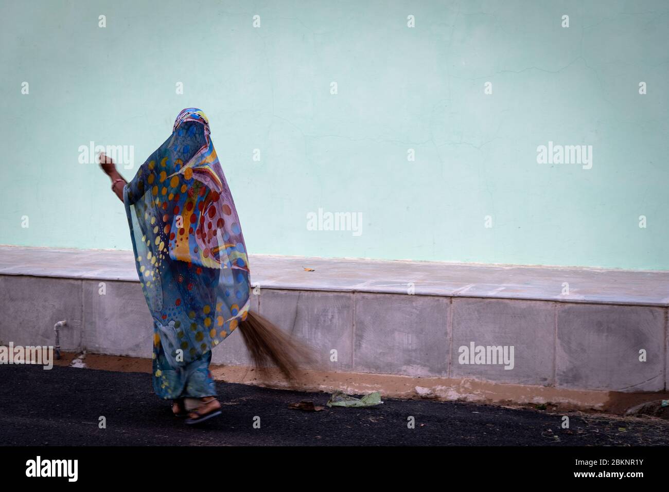Elegante signora indiana che spazzano. Sfondo blu chiaro. Mandowa, Rajasthan, India Foto Stock
