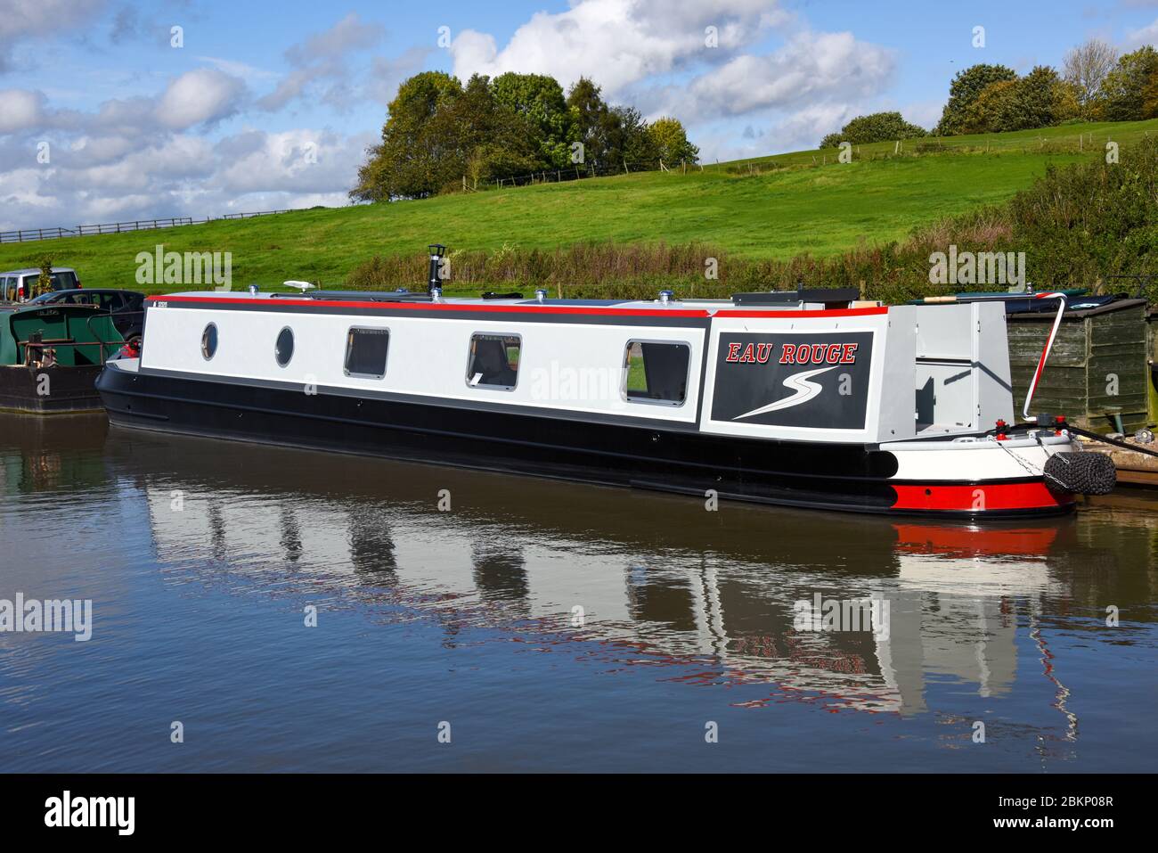 Narrowboat chiamato Eau Rouge ormeggiato sul canale nel Regno Unito. Foto Stock