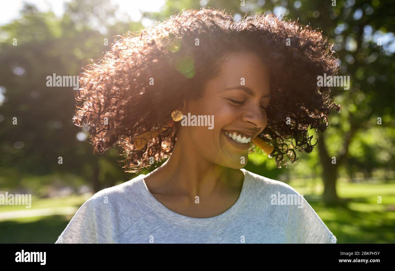 Ridendo giovane donna che si attorciglia i capelli in una giornata di sole Foto Stock
