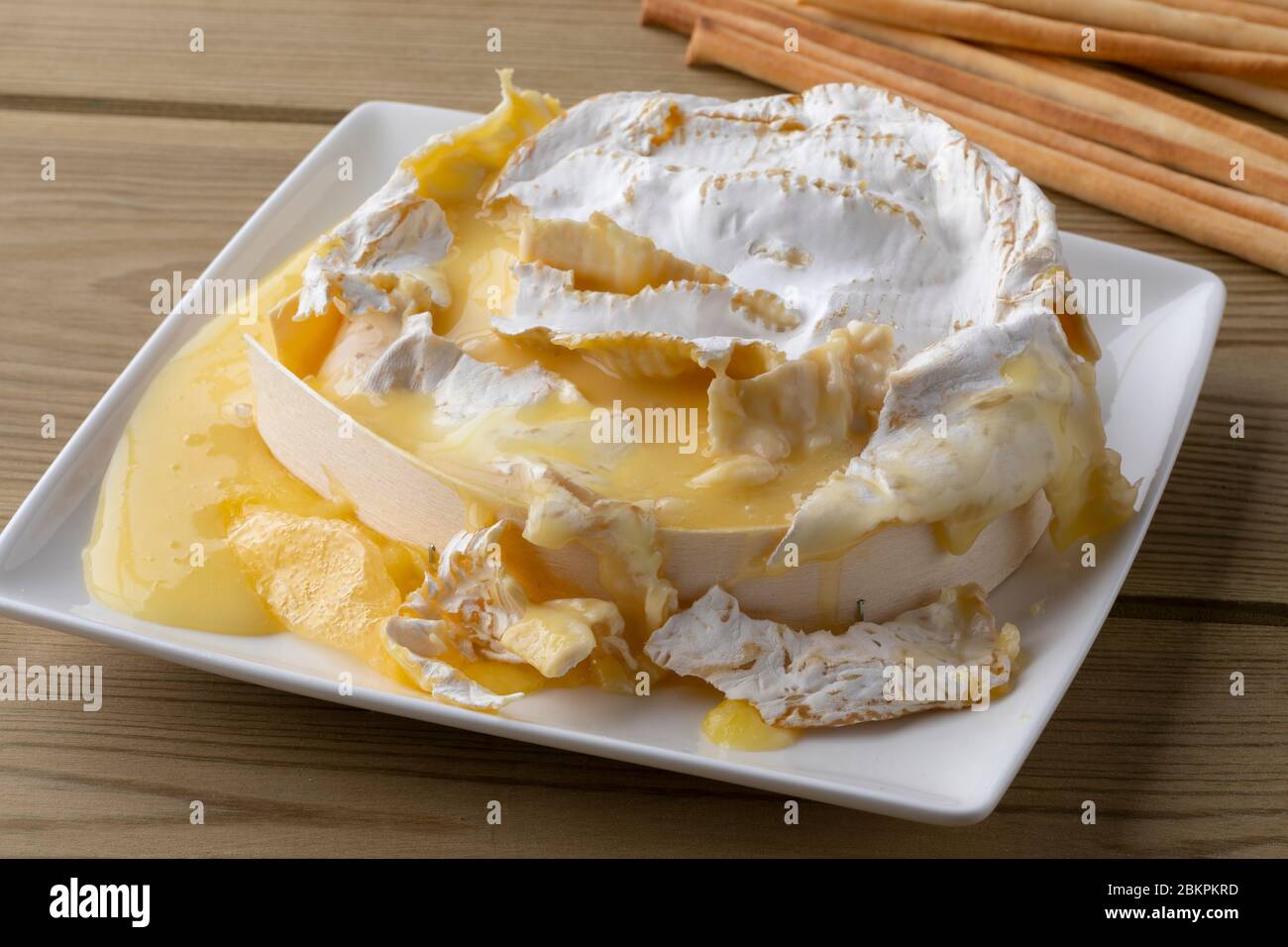 La francese Camfondue si avvicina con bastoncini di pane su un tavolo di legno Foto Stock