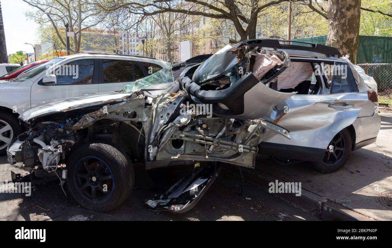 un totale, abbandonato auto metà sul marciapiede, metà sulla strada. Corpo color argento con airbag esploso visibile attraverso il vetro rotto Foto Stock
