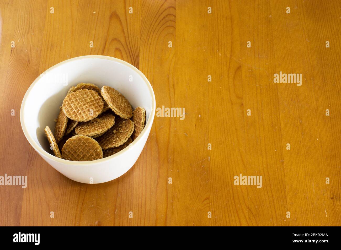 Ciotola di mini stroopwafels su un tavolo di legno. Uno stroopwafel è un biscotto tradizionale olandese fatto da due strati sottili di pasta cotta Uniti da un caramello Foto Stock