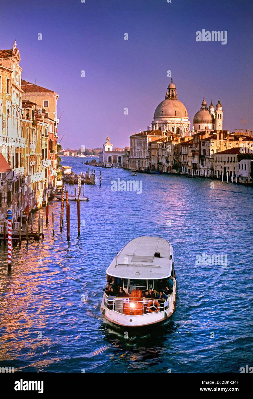 VAPORETTO VAPORETTO CANAL Grande DI VENEZIA con trasporto in vaporetto e vista senza tempo del tramonto lungo il Canal Grande fino alla Basilica di Santa Maria della Salute e alla sua cupola simbolo Venezia Italia Foto Stock