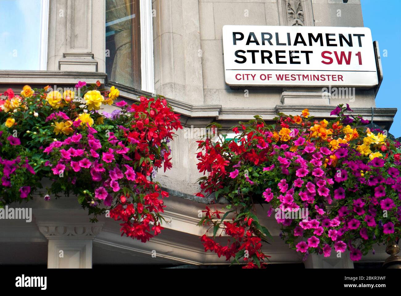 'Parliament Street SW1 ULEZ City of Westminster' cartello stradale con petunias in cesti pendenti, Houses of Parliament e 10 Downing Street London SW1 Foto Stock