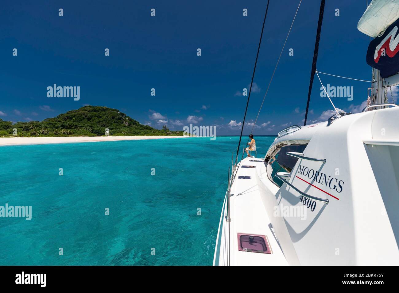 Seychelles, Cousine Island, donna a bordo di una barca ad ancora su acqua turchese Foto Stock