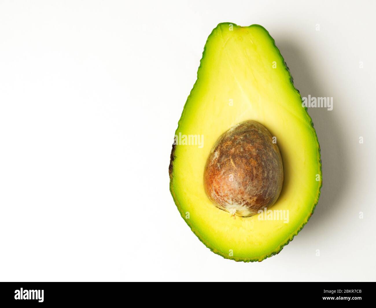 Mezzo avocado con la pietra lasciata su sfondo bianco Foto Stock