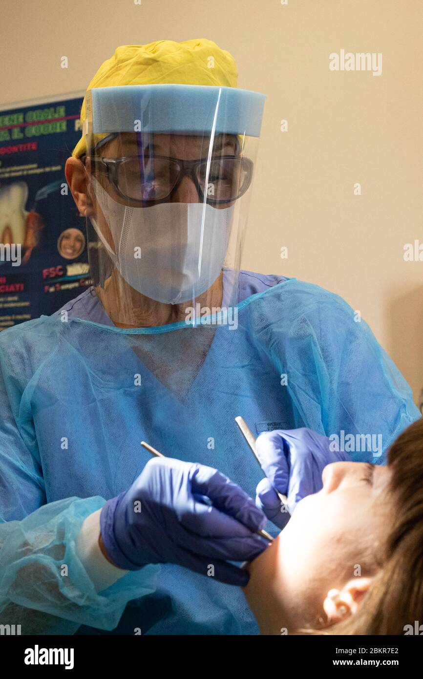 Asti, Italia. 04 maggio 2020. Dentista che indossa una visiera protettiva  durante la cura del paziente. Come lo studio dentistico si è attrezzato per  garantire la sicurezza del coronavirus. (Foto di Norberto