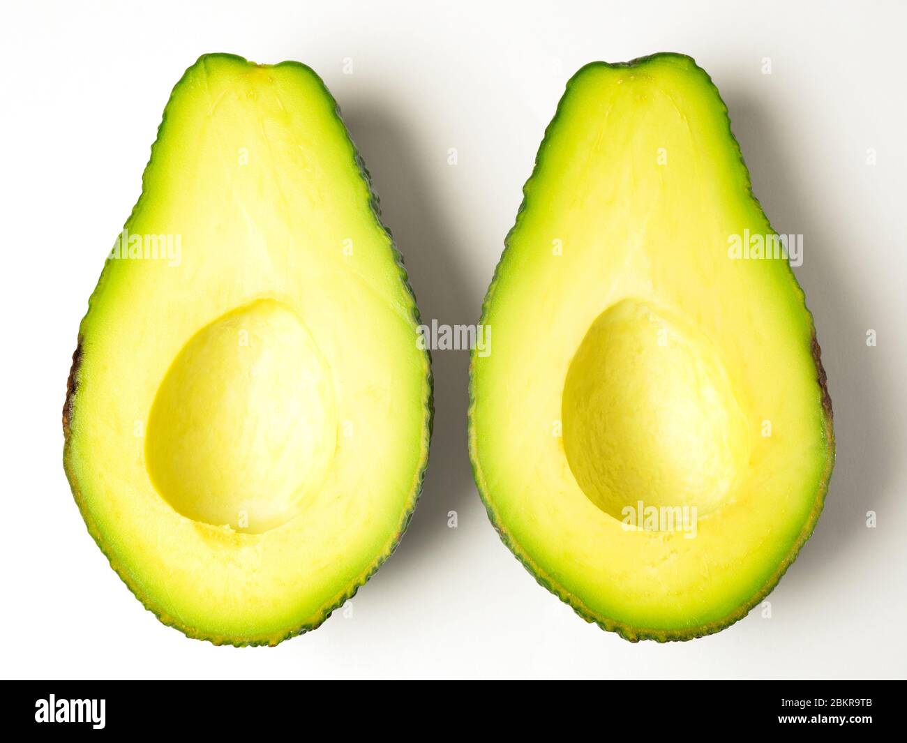 Due avocado si metà allo stesso modo con la pietra rimossa su uno sfondo bianco Foto Stock