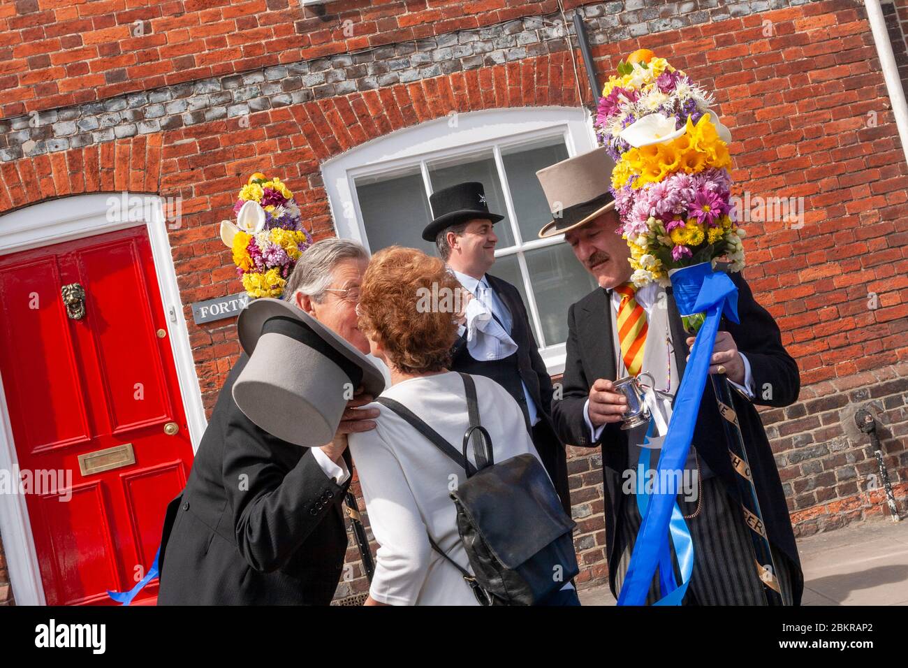 Tutti gli uomini che danno il bacio tradizionale con Orangeman in background, tutti Day, tradizionale Festival annuale Hocktide, Hungerford, Berkshire, Inghilterra Foto Stock