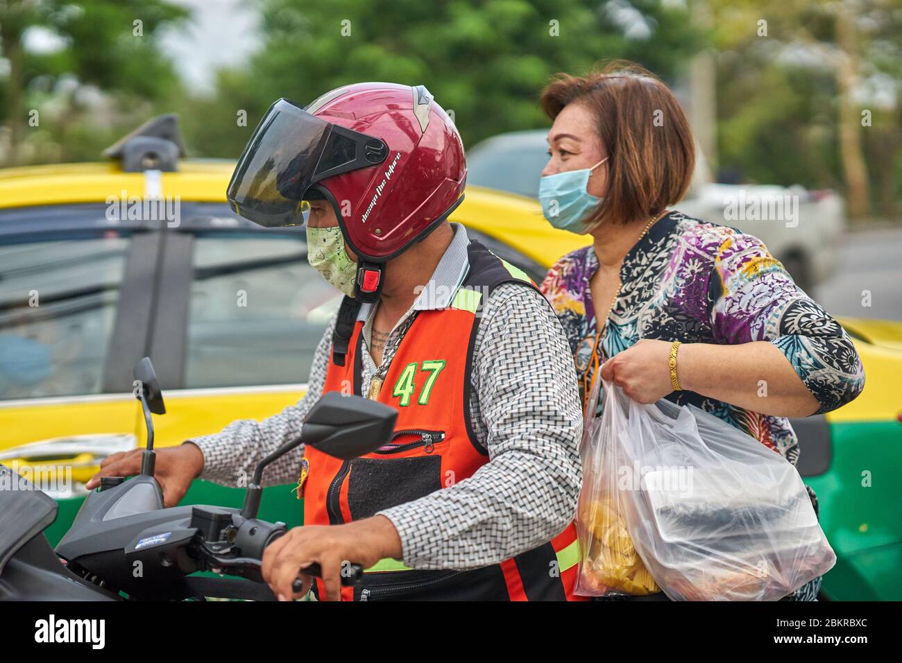 Un tassista e passeggero di motocicletta, indossando maschere protettive per il viso, a Pathumthani, in Thailandia, nel maggio 2020. Foto Stock