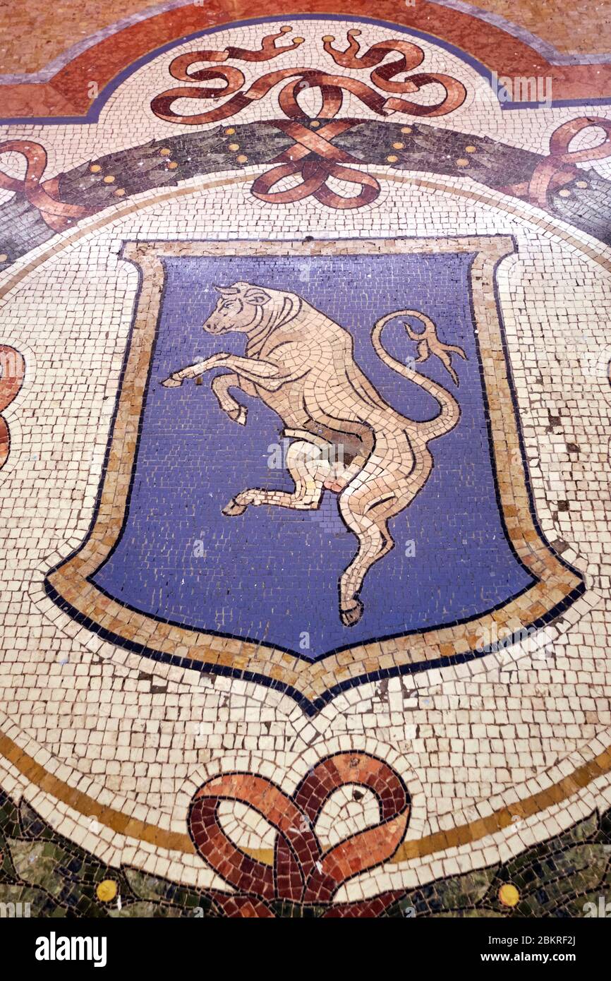 Italia, Lombardia, Milano, Galleria Vittorio Emanuele II, la tradizione dice che se una persona gira intorno tre volte con un tallone sui testicoli della bolla di Torino stemma questo porterà buona fortuna. Questa pratica provoca danni al mosaico: Un buco che si sviluppa sul posto dei genitali del toro. Foto Stock