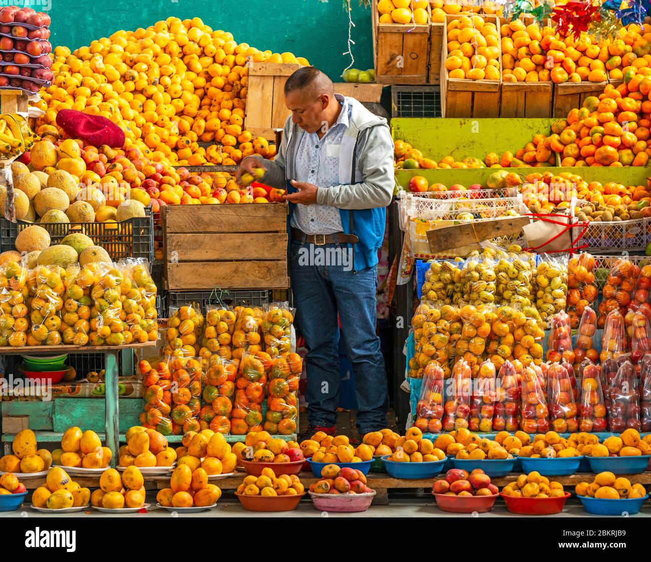 Venditore di frutta nel mercato locale di Otavalo vicino Quito, Ecuador. Faccia affilata, frutta non affilata. Foto Stock