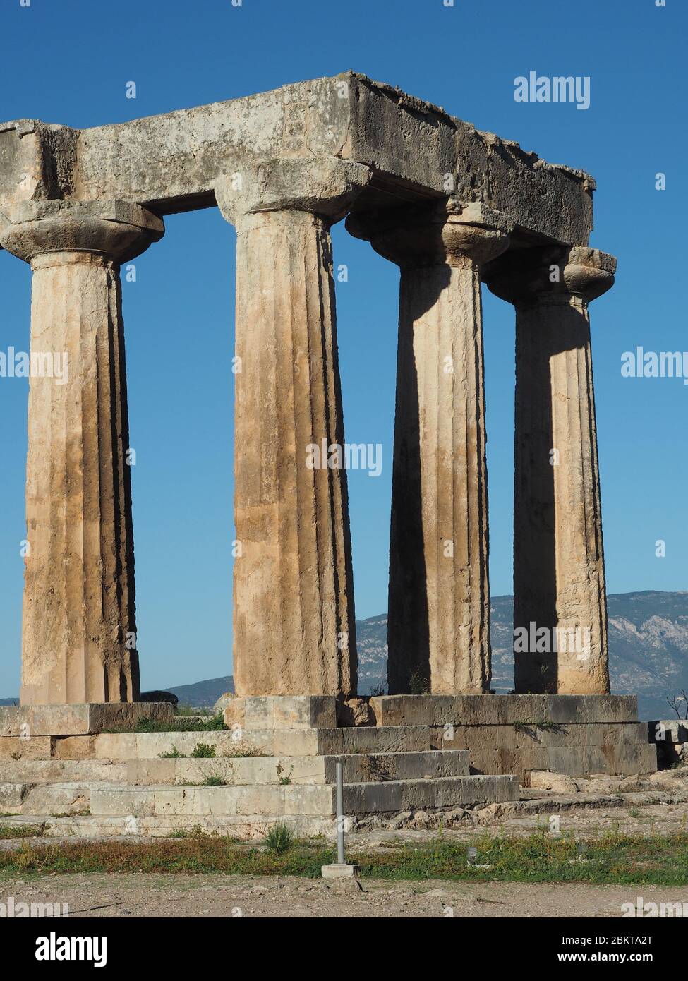 Colonne doriche del Tempio arcaico ad Apollo a Corinto, Peloponneso, Grecia contro un cielo blu Foto Stock