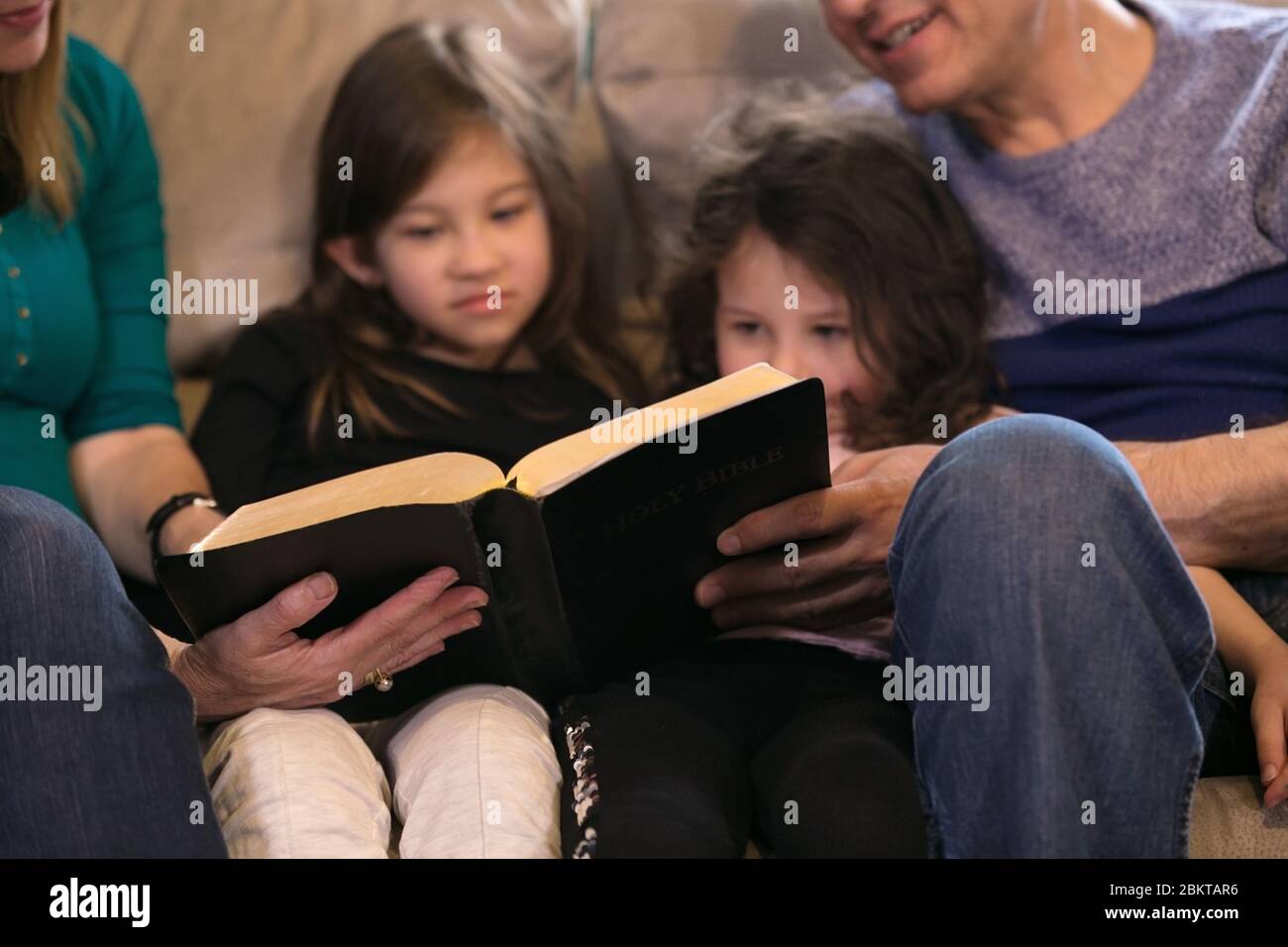 Nonni che insegnano i nipoti sulla Sacra Bibbia Foto Stock