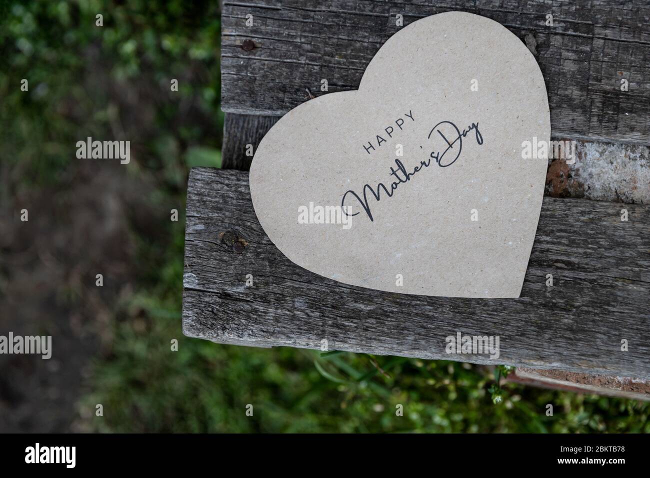 Felice Festa della mamma scritta su una carta su una vecchia panchina rustica Foto Stock