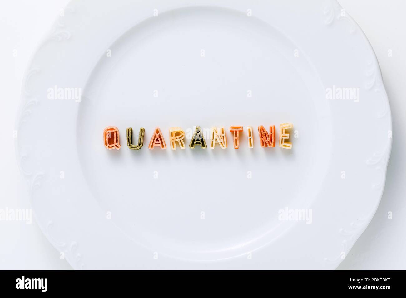 Quarantena di parole da pasta secca multicolore su un piatto bianco. Foto Stock