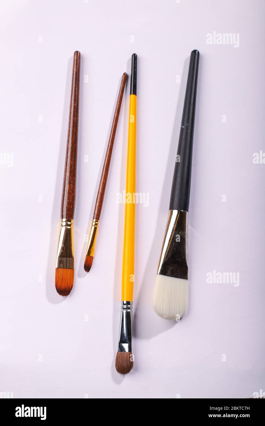 Pennelli d'arte di diverse dimensioni su sfondo bianco. Quattro spazzole per pittura, colpo verticale Foto Stock