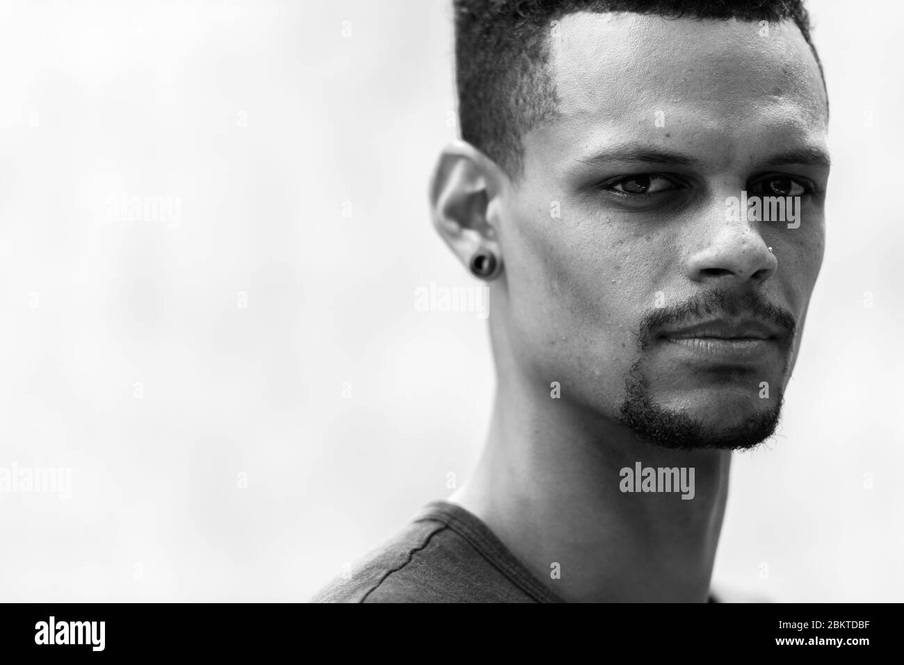 Volto di giovane bell'uomo africano bearded con orecchini in bianco e nero Foto Stock